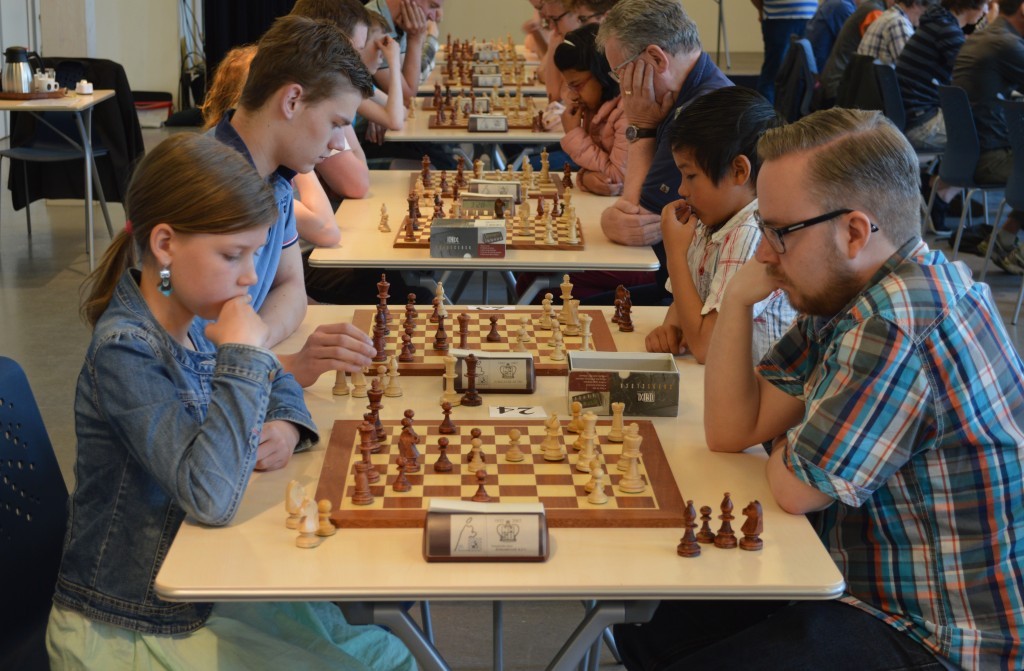 De andere kant van de lange tafel, ronde 1, bord 24. Jan-Pjotr Komen (wit, Magnus) neemt het op tegen jeugdspeelster Jule Cordes (VAS).