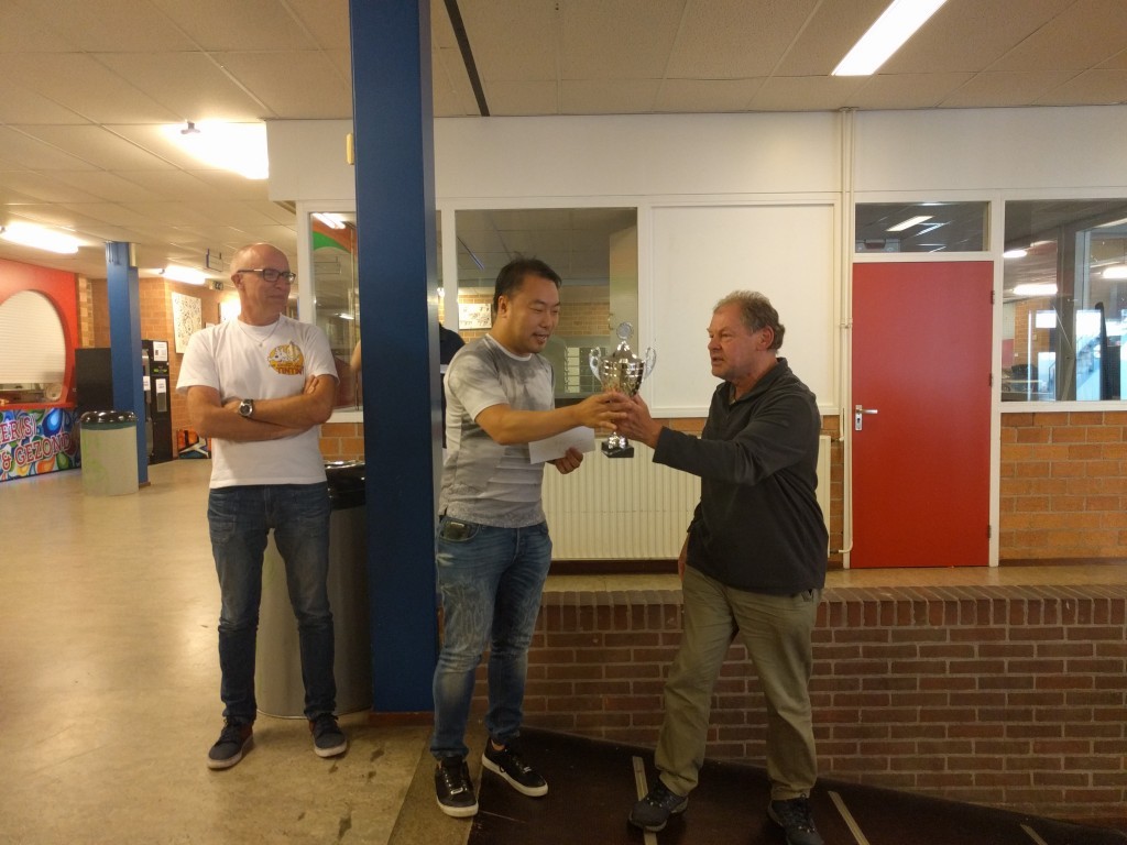 Voorzitter Co Buysman overhandigt de wisselbeker aan de nieuwe Open Hoorns kampioen Yong Hoon de Rover.